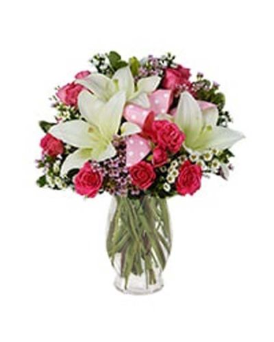 <p>Light pink roses, pink waxflower, white Asiatic lilies and white Monte Casino blooms dance vividly around a playful pink polka dot ribbon in this glorious arrangement set in a pink fluted vase.</p>
