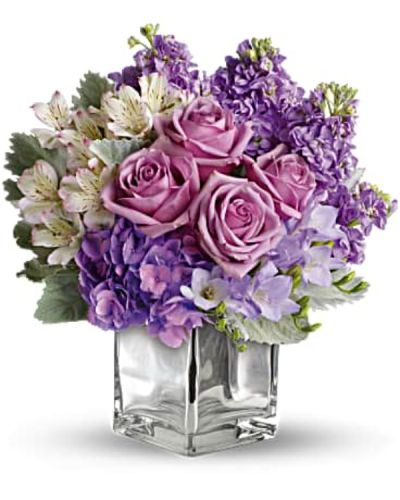 Visions of sugar plum fairies dance to life with this magical bouquet. Lush lavenders, frosty whites and silvery greens look romantic and refreshing inside a cool cube vase.
Robust roses, delicate hydrangea and feminine stock make a cool collection inside an icy, clear glass cube vase.