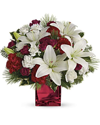 <p>Filled with holiday charm. Red spray roses and white asiatic lilies are arranged to perfection in our red mirrored cube.</p>