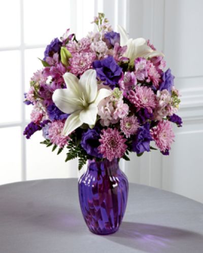 Everyone loves a little purple in their life - it's elegance, it's twilight magic, it's expression of the unexpected. Send your recipient every shade of purple nature can supply with this flower arrangement, bringing together lavender gilly flower, purple double lisianthus, lavender chrysanthemums, purple Peruvian Lilies, and purple statice, accented with white Asiatic Lilies and lush greens presented in a modern purple glass vase.