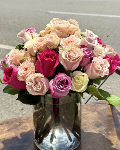 <p>Colorful roses and spray roses in a beautiful, lush design in a cylinder.</p>