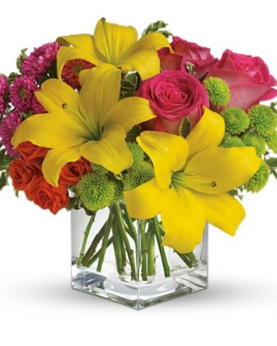 <p>Rich pink roses orange miniature orange baby roses and green accent flowers in a glass cube</p>