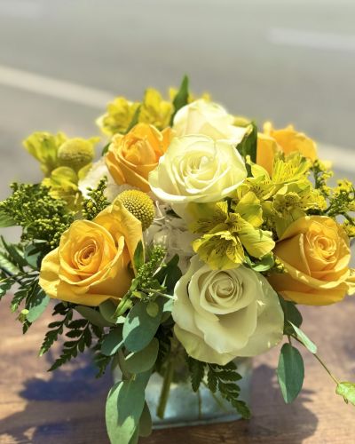 White hydrangeas yellow and white roses yellow alstroemeria designed in a glass cube