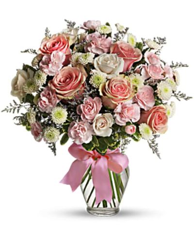Pretty pink roses, spray roses and miniature carnations, white button spray chrysanthemums, lavender limonium and green pittosporum fill a spring glass vase that's wrapped with a pink satin ribbon. It's confection perfection!