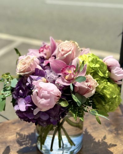 Vibrant hydrangeas, perfectly pink roses, fragrant peonies cymbidium orchids and fresh greenery thoughtfully designed in a glass cylinder.