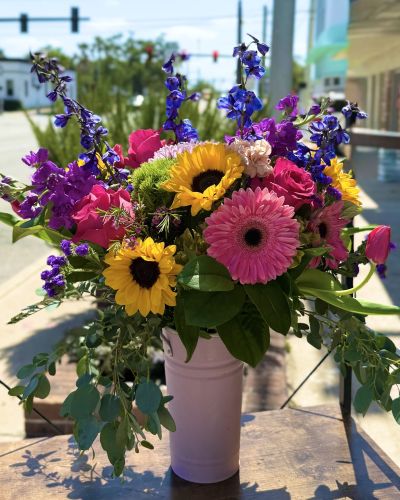 <p>Colorful blooms dripping from our keepsake baby pink vessel featuring Florida sunflowers, hot pink roses, rich blue delphinium fragrant purple stock tulips and much more!</p>